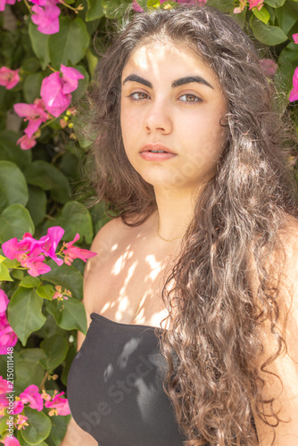 Young woman enjoying warm sunlight among pink bougainvillea flowers