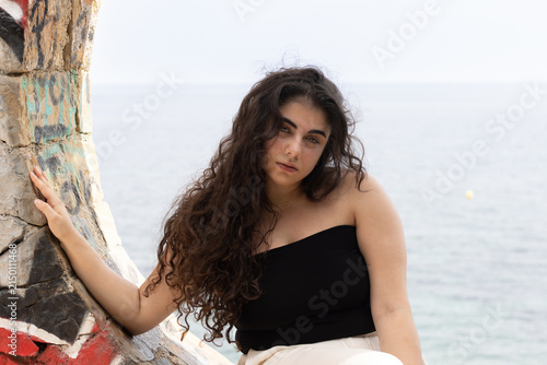 Young woman posing by graffiti wall near the sea