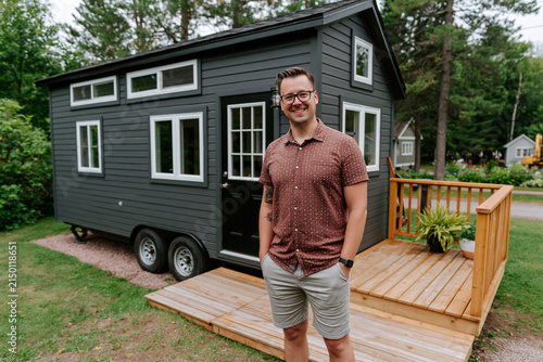 A man stands outside a small home on wheels