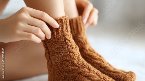 Woman wearing cozy brown knitted socks while sitting at home for warmth and relaxation during the cold winter season concept