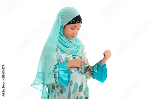 Charming young Asian Muslim child using touchpad computer for online learning e-learning concept.