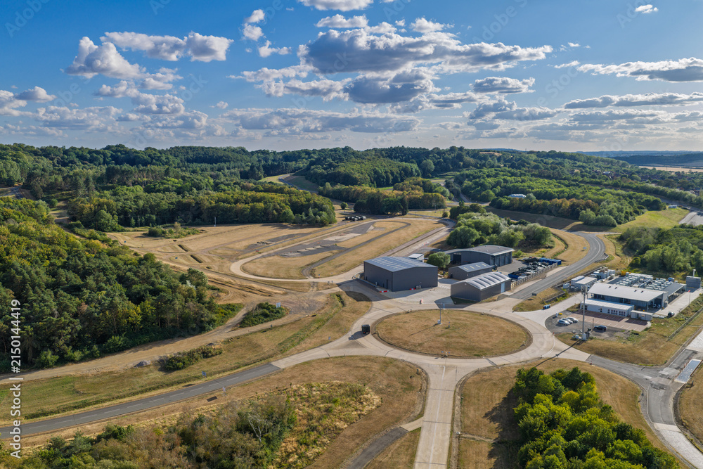 Fototapeta premium Sunny Rural Vehicle Testing Facility With Specialized Tracks and Forest