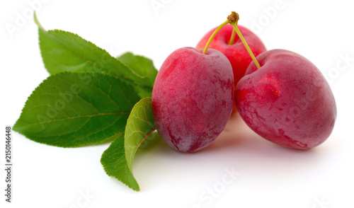 Foto Red plums with green leaves isolated on white background.