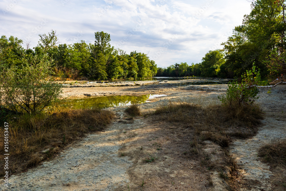 Fototapeta premium Partially dried-up course of the Ariège river in summer 2026, marked by severe heat waves and significant drought, seen from the Ramier de la Riverotte at Clermont-le-Fort