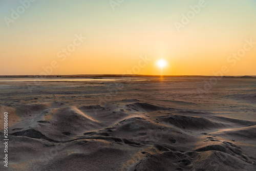 Sunset over the sand dunes and shallow waters of the salt lake