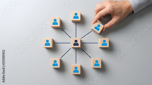 Businessman building organizational structure using blue wooden blocks with person icons on grey background.