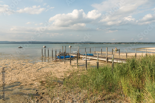 Low water level at Lake Constance: Stranded boats on a dry lake bed next to a wooden jetty during a summer drought in Berlingen, Switzerland.
