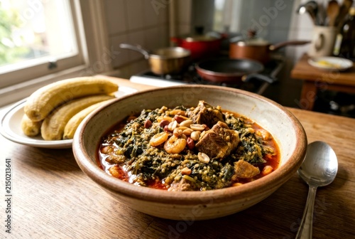 Traditional Cameroonian Ndole Stew Served with Steamed Plantains in a Cozy Home Kitchen Setting