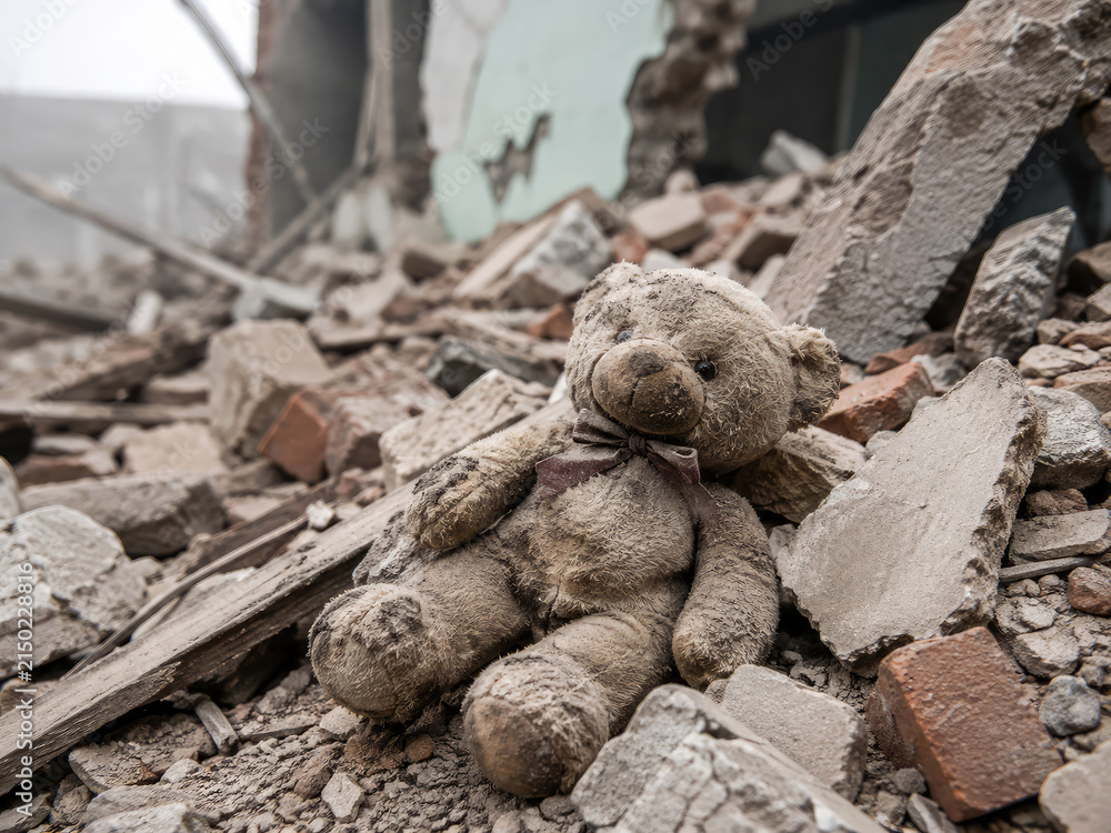 Fototapeta premium Teddy Bear in Building Rubble After Disaster Symbolizing Children Affected by War