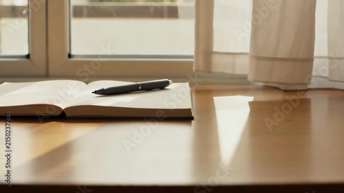 Open journal with a pen on a sunny wooden desk