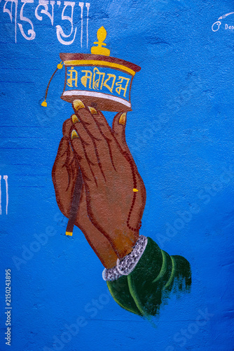 Fotografía A hand holding a Tibetan prayer wheel painted on a blue wall