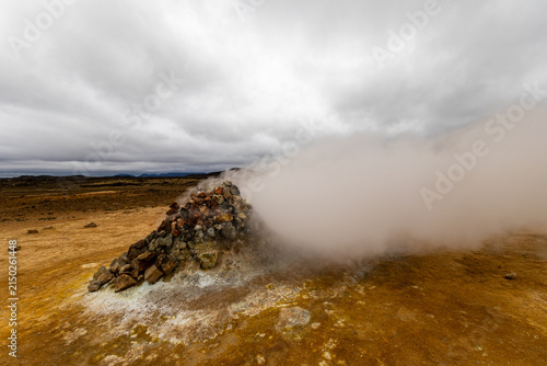 Fotografie Steam venting intensely from a stone cairn fumarole surrounded by sulfur deposit