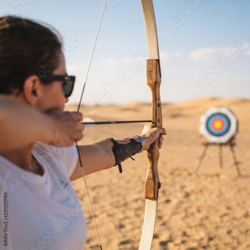 Woman Aiming and Practicing Archery Outdoors with Bow and Target