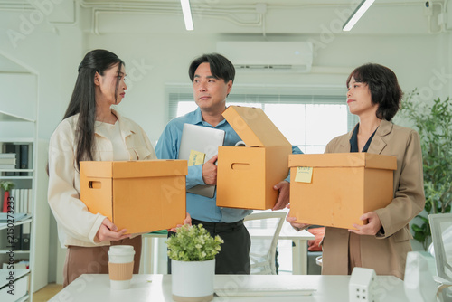 Canvas Print Three colleagues stand face to face holding boxes of packed belongings labeled w