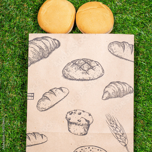Freshly baked bread and crumpled paper bag on a grass background .Top view.
