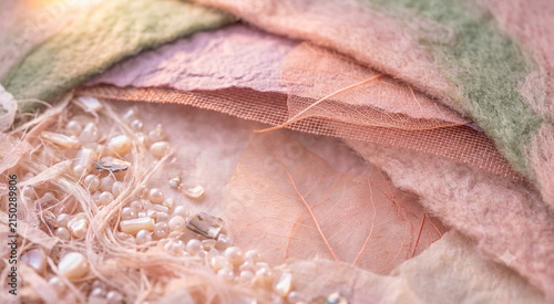 Delicate botanical textile texture with dried leaves and decorative beads in soft pink tones