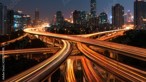Streaking car lights create a dynamic glow over an intricate multi-level highway interchange at night