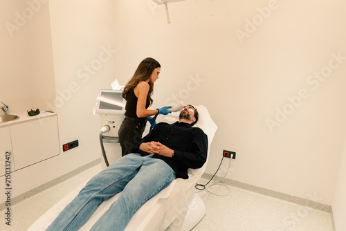 Derm examines male patient skin at follow-up in specialized clinic.