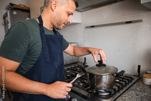 Man Checking Pot While Cooking Dinner at Home Stove