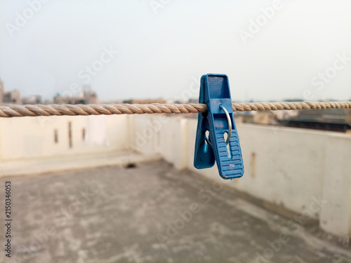 Obraz na płótnie A blue plastic clothes pin or clothes peg for house hanging on rope isolated on