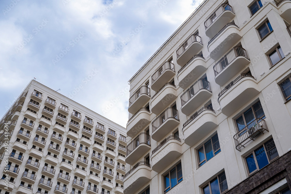 Fototapeta premium Close-up view of modern apartment buildings with curved balconies and dramatic cloudy sky.