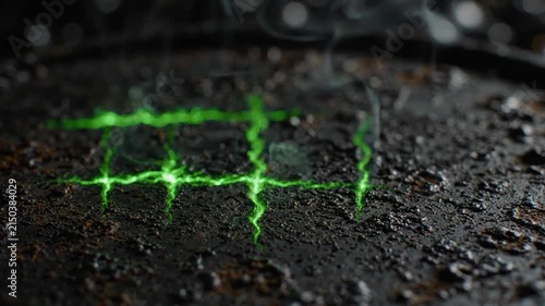 Bright green laser grid burning on a dark metal surface with sparks