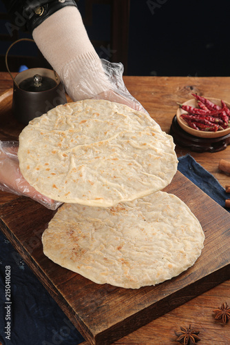 Fotografie Chef making fresh homemade flatbread tortillas on wooden board with spices and c