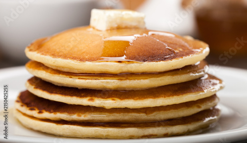 Obraz na plátně Stack of fluffy homemade pancakes with melting butter and dripping maple syrup o
