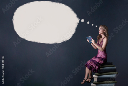 Fotografía Mujer sentada en una pila de libros con globo de diálogo en blanco  para publicidad
