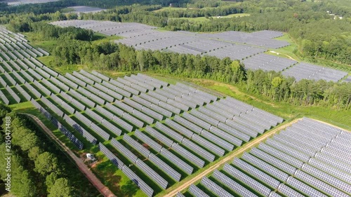 Aerial View Of A Large Solar Panel Farm Generating Clean Renewable Energy In A Forested Landscape
