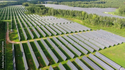 Aerial View Of A Large Solar Panel Farm Generating Clean Renewable Energy In A Forested Landscape