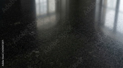 Close-up of a dark speckled granite countertop surface with reflections.