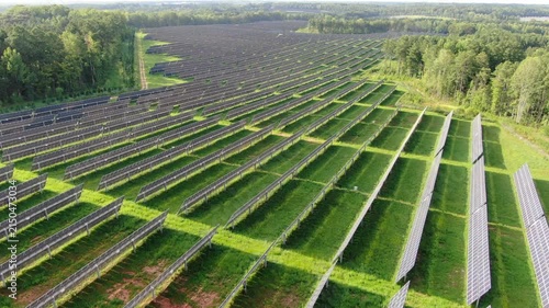 Aerial View Of A Large Solar Panel Farm Generating Clean Renewable Energy In A Forested Landscape