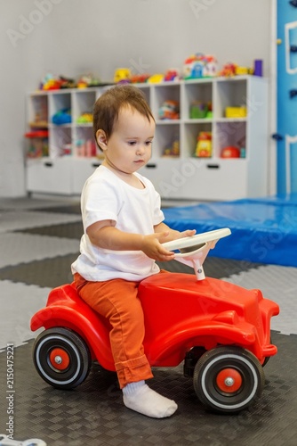Obraz na płótnie Toddler riding toy car to develop balance and coordination at daycare