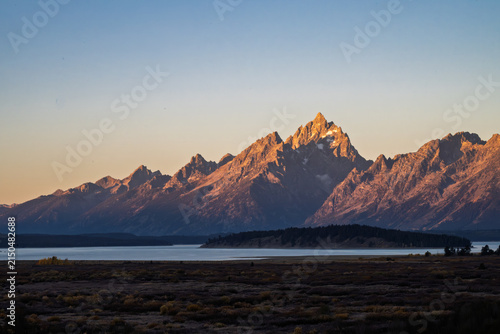 Golden sunrise light illuminating the rugged peaks of the Grand Teton mountain range