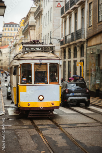 Traditional yellow Lisbon tram traveling along narrow historic streets lined with old buildings, capturing the timeless atmosphere of Portugal’s iconic public transport system.