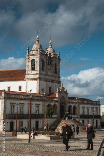 Historic church building with ornate towers and traditional Portuguese architecture beneath blue sky and clouds creating cultural travel and religious landmark scenery scene.