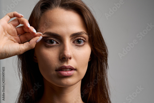 Evaluating droopy skin condition before a surgical eyelid lift operation by gently pulling the upper fold during a medical aesthetic consultation
