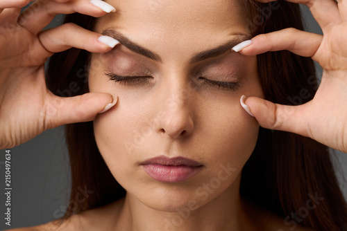 Closeup portrait of a woman demonstrating the condition of her upper and lower eyelids by touching the skin with her fingers. Blepharoplasty and eyelid correction concept