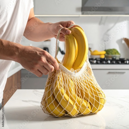 Person holding ripe yellow bananas in a reusable cotton mesh string bag for sustainable zero waste grocery shopping in modern kitchen