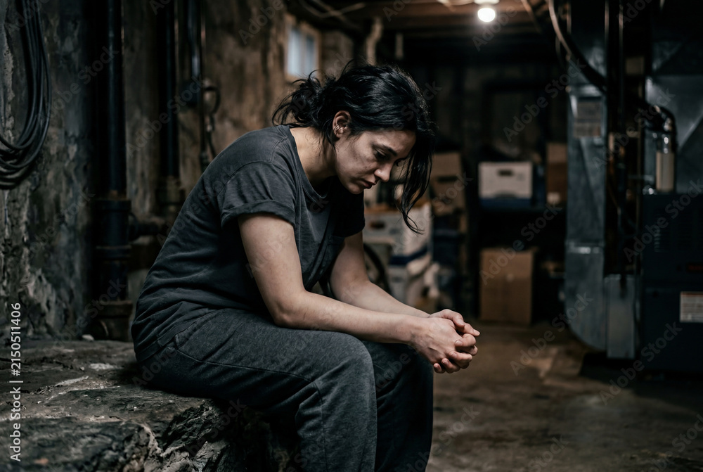 Obraz premium Depressed woman sitting alone in dark basement