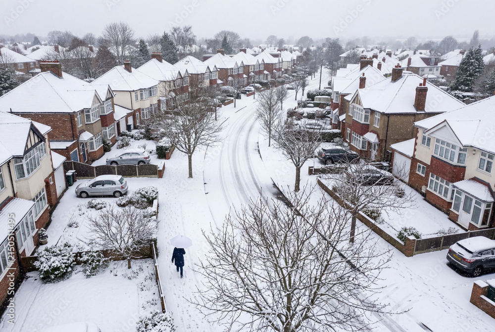 Fototapeta premium Aerial view of suburban street and houses covered in winter snow
