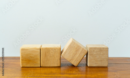 Fotografie Wooden blocks arranged on a wooden surface, with one block falling to represent failure, disruption, risk, or chain reaction