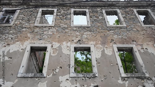 Burned house destroyed by artillery in war. Ruined home showing consequences of war. Devastated building after military attack.