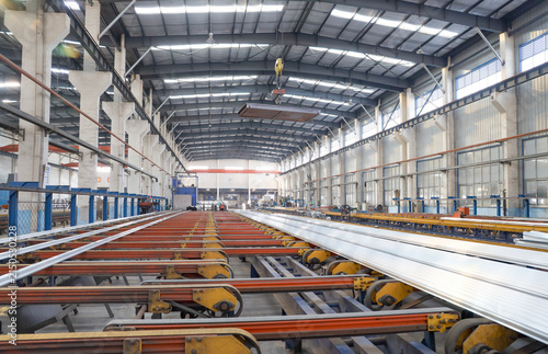 Aluminum extrusion production line inside large industrial workshop, factory manufacturing scene