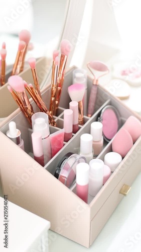 Woman putting brush into makeup organizer at table indoors, closeup