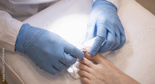 Professional podiatrist providing medical foot treatment using tools in a clean clinical setting with podiatrist