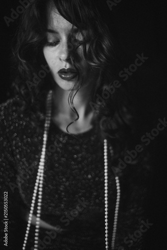 Bild auf Leinwand Dramatic Black and White Portrait of Curly Brunette in White Beads