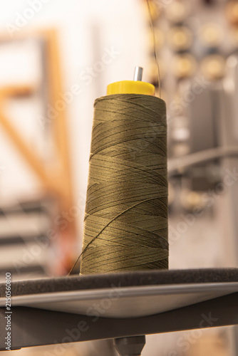 фотографія close up of a thread spool beside manufacturing equipment