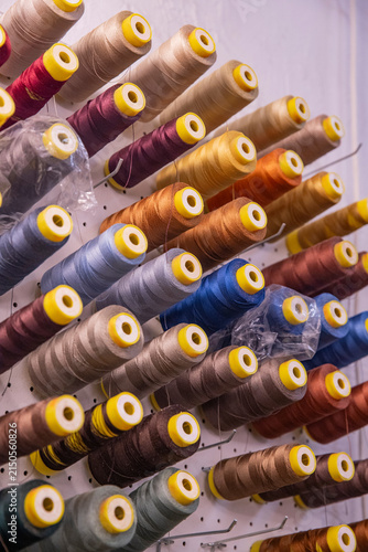 English: colorful spools of thread on industrial sewing equipment